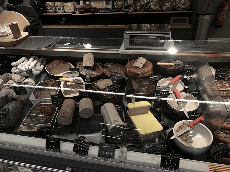 Cured meats such as salami and prosciutto displayed in a glass case under good lighting.
