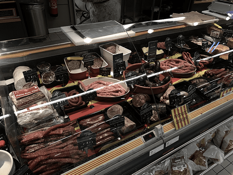 Meat display case with assorted sausages and meats.