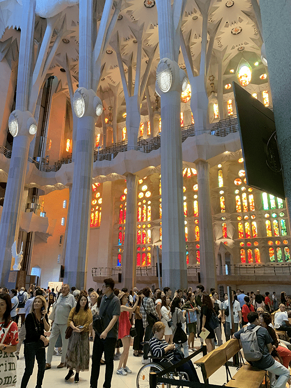 Grand building interior with stained glass windows, intricate carvings, and a polished stone floor.