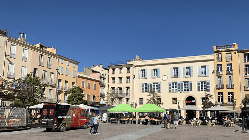 Vibrant city square scene featuring buildings, food truck, and outdoor seating.