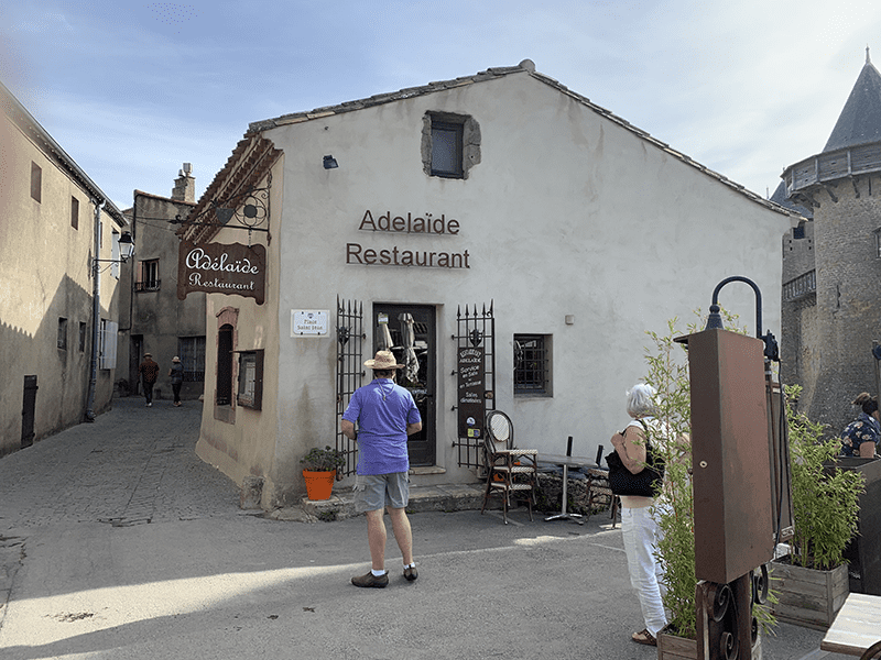 Rustic stone building with wooden door and sign reading Adelaide Restaurant.