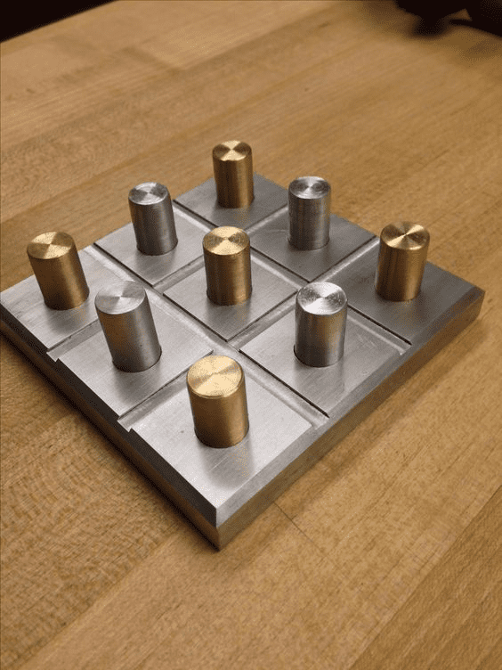 Metal plate with brass and steel cylinders in a grid pattern.