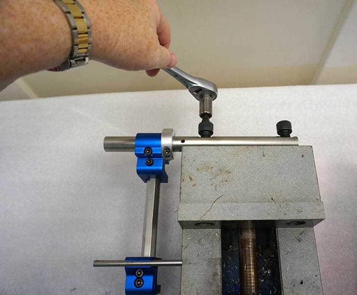 A machinist is using a tool to tighten a piece of metal in a vise.