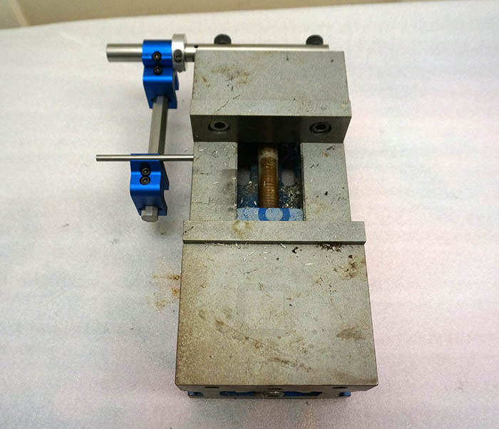 A machinist vise with a blue handle on it.