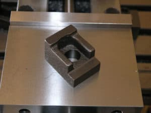 Silver metal object with a square shape and central hole.