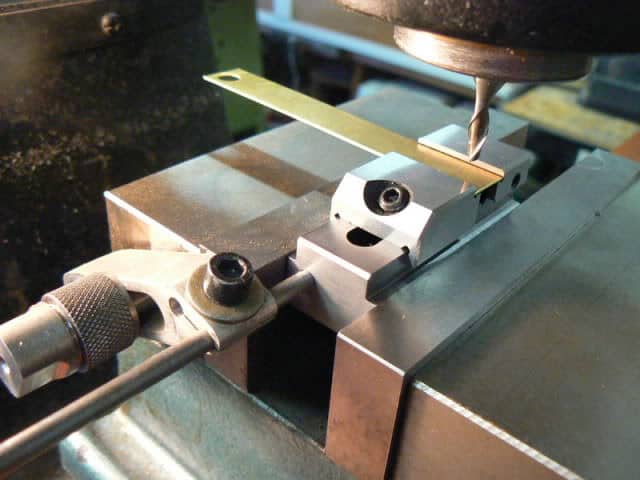 A machinist is using a vise to shape a piece of metal.