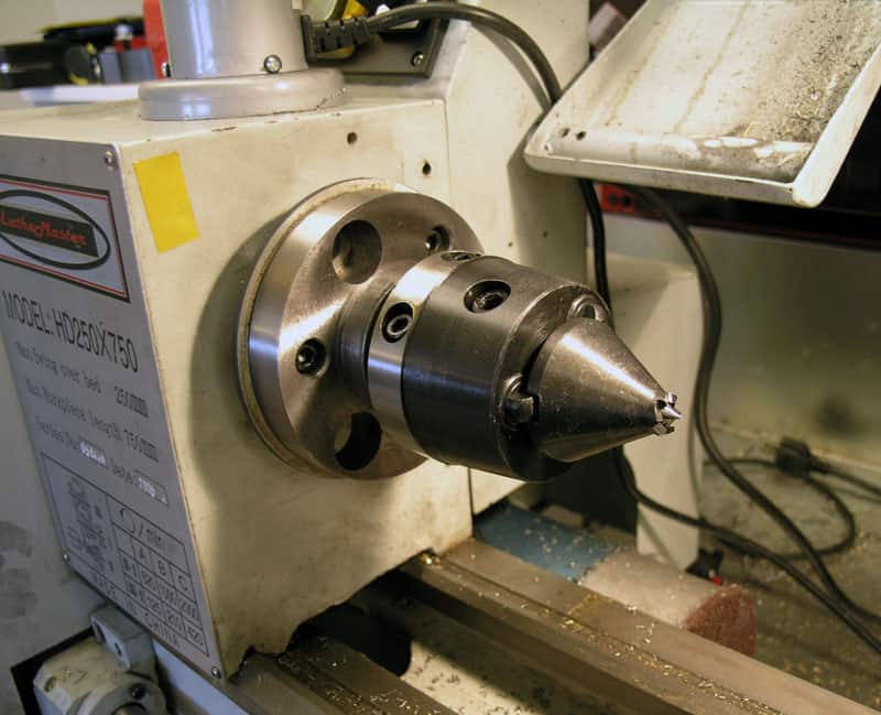 A lathe chuck mounted on a machine tool, featuring a conical shape and central hole.