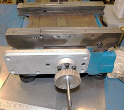 Cast iron metalworking vise with flat base, vertical jaws, and cylindrical handle.