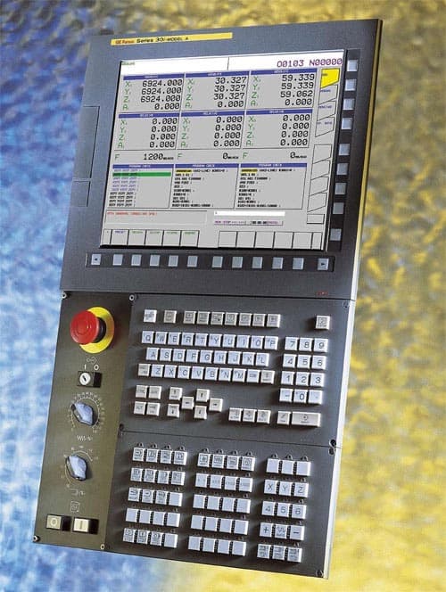 Industrial control panel with multiple buttons, dials, and digital display in a machining or manufacturing setting.