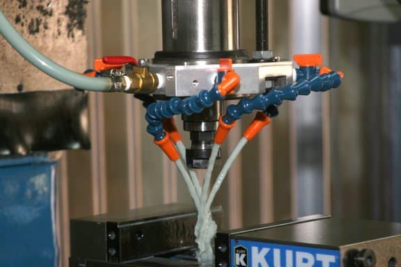 Machine tool with coolant system, Kurt chuck, and metal base plate in a workshop setting.