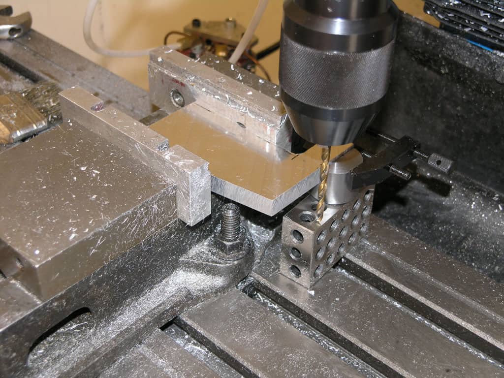 A black drill bit milling aluminum on a metal machine.