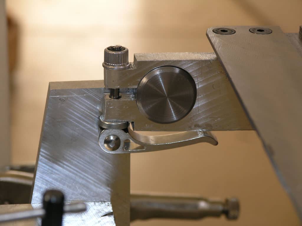 Silver metal tool with round knob and small cylindrical protrusion.