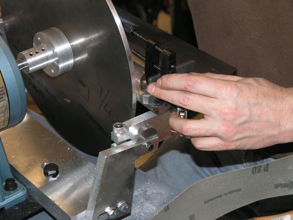 Machinist operating a lathe or milling machine, hands visible, in a workshop background.
