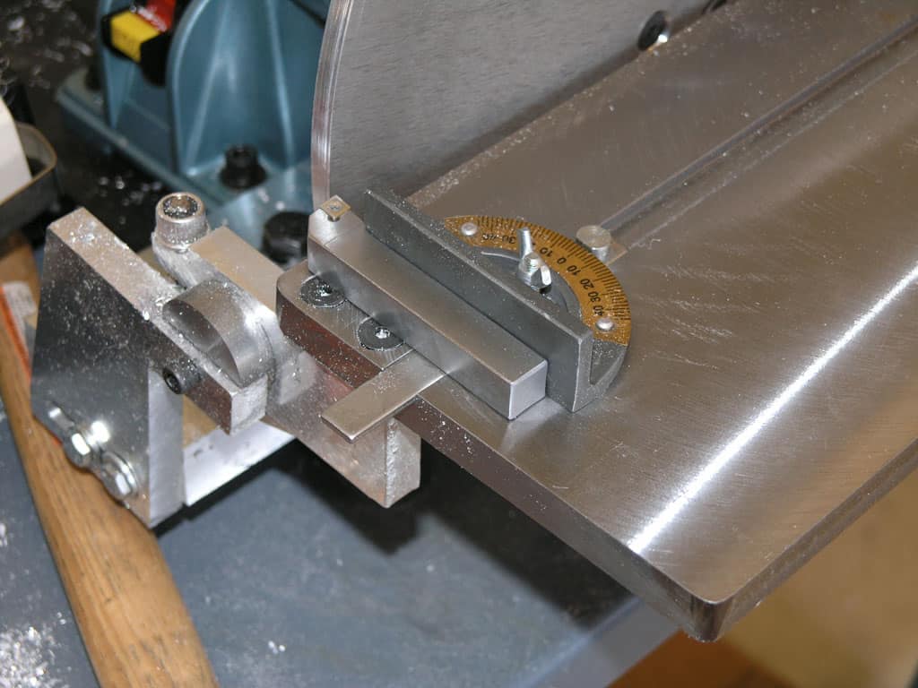 Silver metal machine with wooden handle and yellow gauge on a gray background.