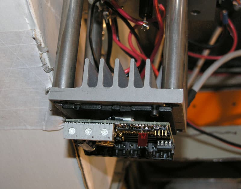 Metal power supply unit with wires and circuit boards in a workshop setting.