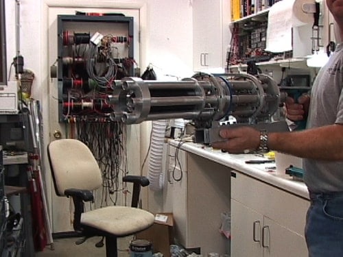 A man holding a machine gun in a workshop.