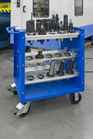 A blue utility cart with various automotive parts and tools organized on its shelves in a CNC machine shop.