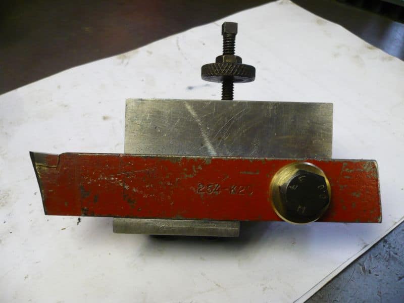 A red and metal CNC bench block tool with a horizontal level, placed on a worn white surface.