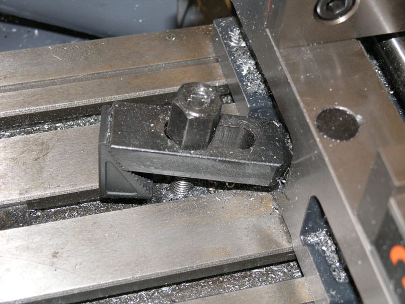 Dark gray metalworking vise attached to an industrial metal working table.