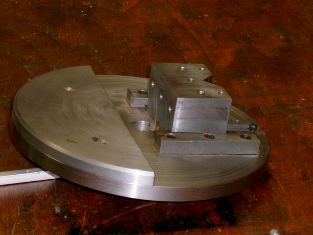 Silver metal object with a flat top and bottom, curved sides, and an unfinished machined appearance.