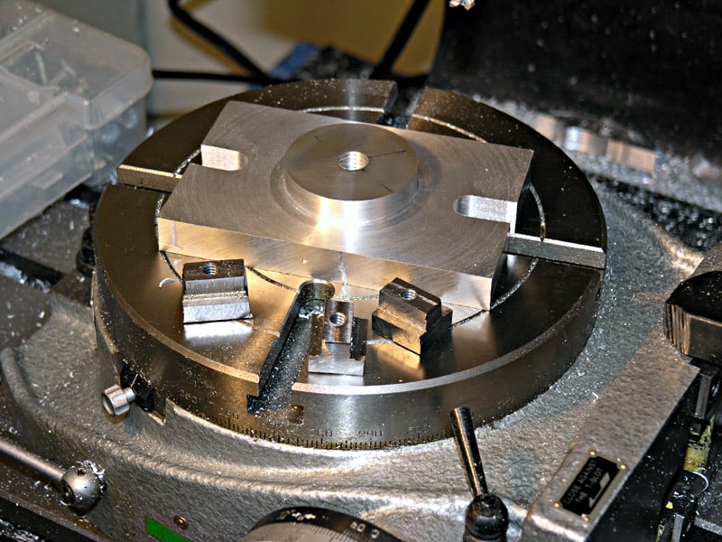 Metal fixture with silver-colored metal construction and four square holes for securing nuts.