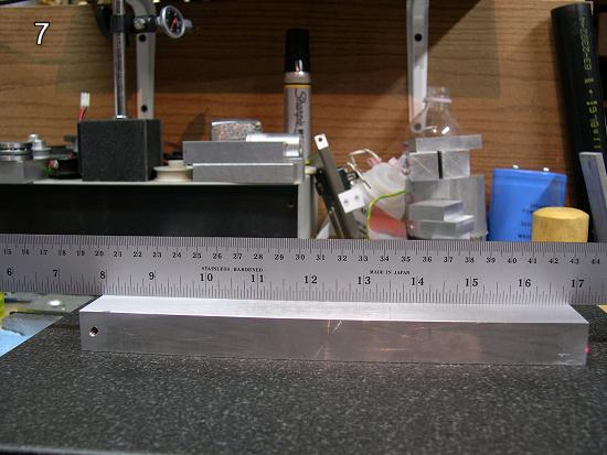 Laser tooling plate with drilled holes on wooden/plastic workbench surrounded by various machinery tools.