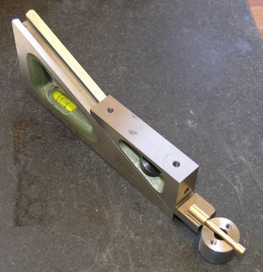 Precision measuring tool with flat surface, markings, and small dial on a metallic base.