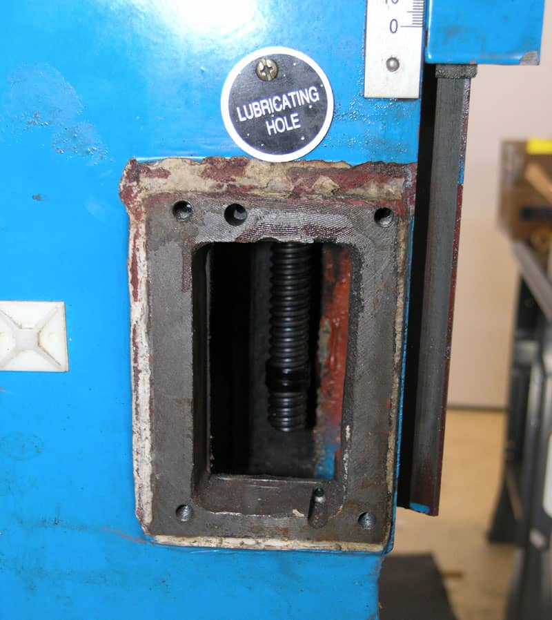 Close-up of an open mechanical compartment on a blue machine showing exposed DIY transfer screws, labeled "lubricating hole.