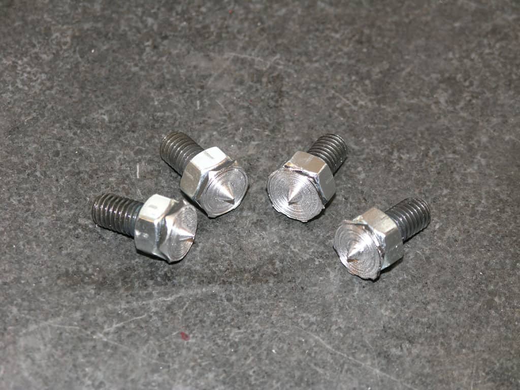 Silver bolts in diamond pattern on gray surface.