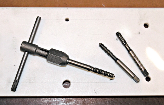 Metal tools with threaded ends arranged on a flat surface.