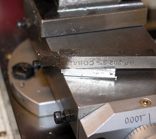 Metal workbench vise with engraved numbers in a machining or machine shop.