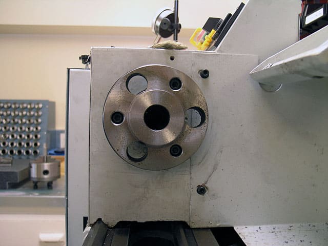 Close-up of a metal lathe spindle in a workshop, showcasing the 6-Jaw Chuck and the machine's detailed components and tools.