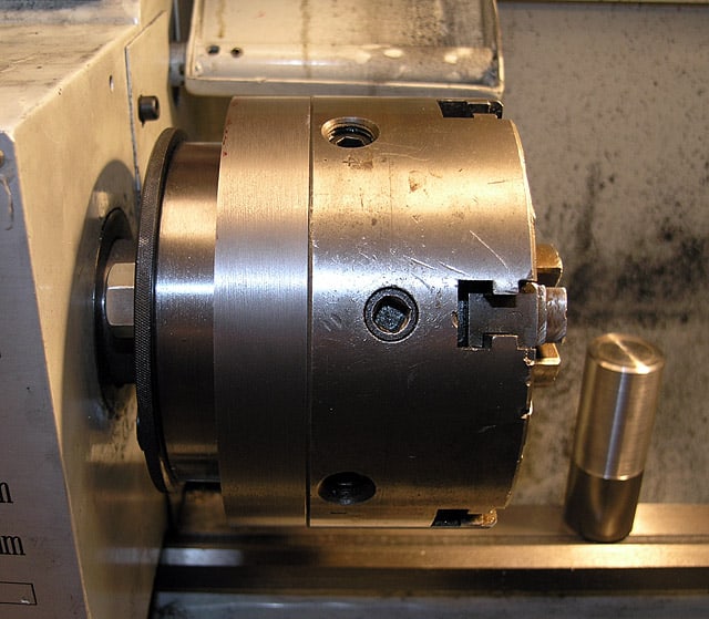 Cylindrical metal part with central hole and small protrusion.