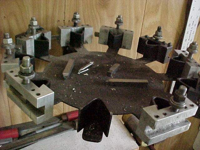 Various metalworking tools and clamps organized on a workshop table, covered in metal shavings and debris, including a dedicated QCTP holder storage area.