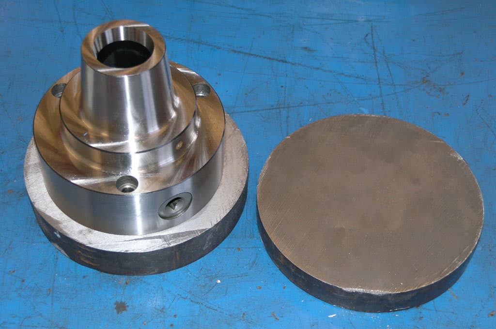 Metal components with cylindrical shape and metallic finish on blue background.
