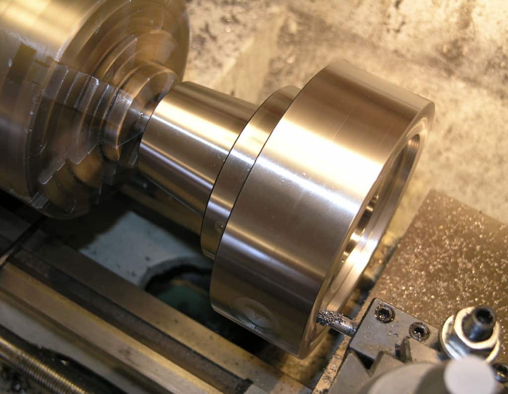Metal part on lathe in machine shop setting.