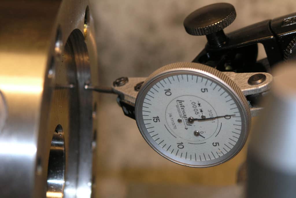 Analog stopwatch mounted on machinery with white clock face and black hands.