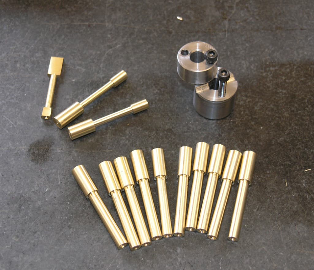 Precision metal parts: brass rods, stainless steel/titanium cylinders, and round metal pieces.