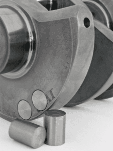 Metallic object with a cylindrical shape and two circular indentations, having a smooth metal finish.