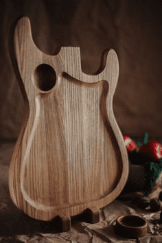 Wooden cutting board shaped like electric guitar.
