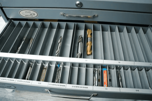 Metal toolbox with drill bit, wrenches, pliers, and other tools.