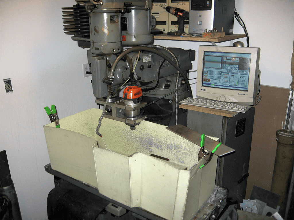 Workshop setup with tools and equipment, including a computer monitor and milling machine.