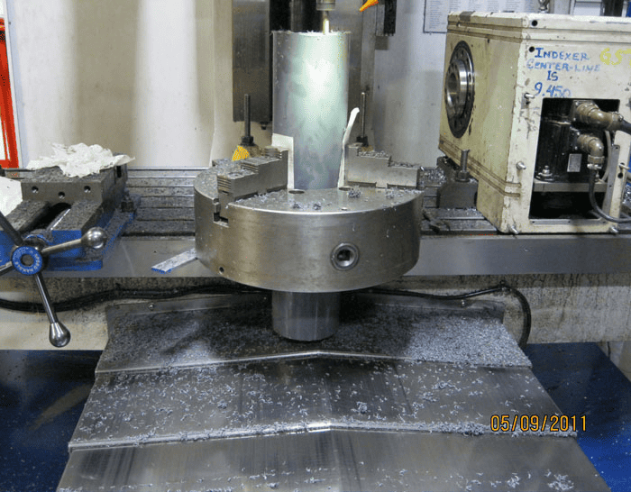 A metal cutting machine set up in a workshop, with tools and equipment visible in the background.