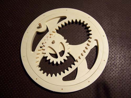 Beige gear with teeth on inner edge and small central hole on dark brown background.